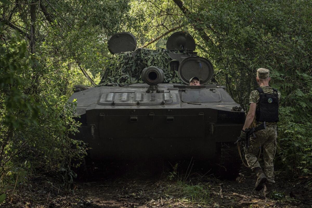 A soldier stands next to an armored vehicle.