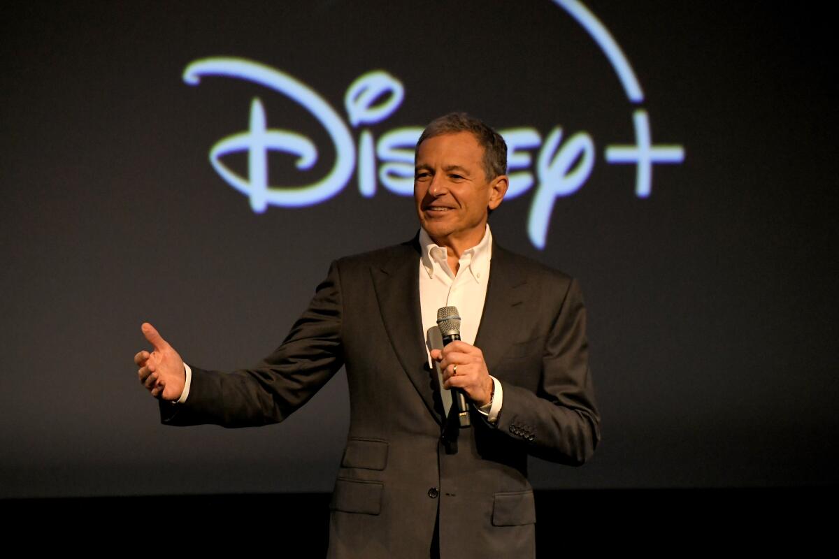 Disney Chief Executive Bob Iger stands holding a microphone.  