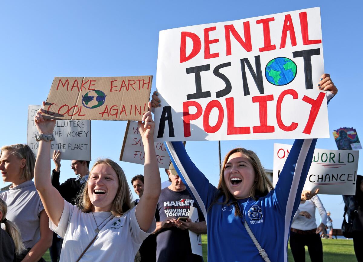 Jordan Pritzl of Aliso Viejo, left, and Merina Addonigio, both from Suka University, hold protest signs during the Climate Strike climate change protest, at Main Beach Park in Laguna Beach in September 2019.