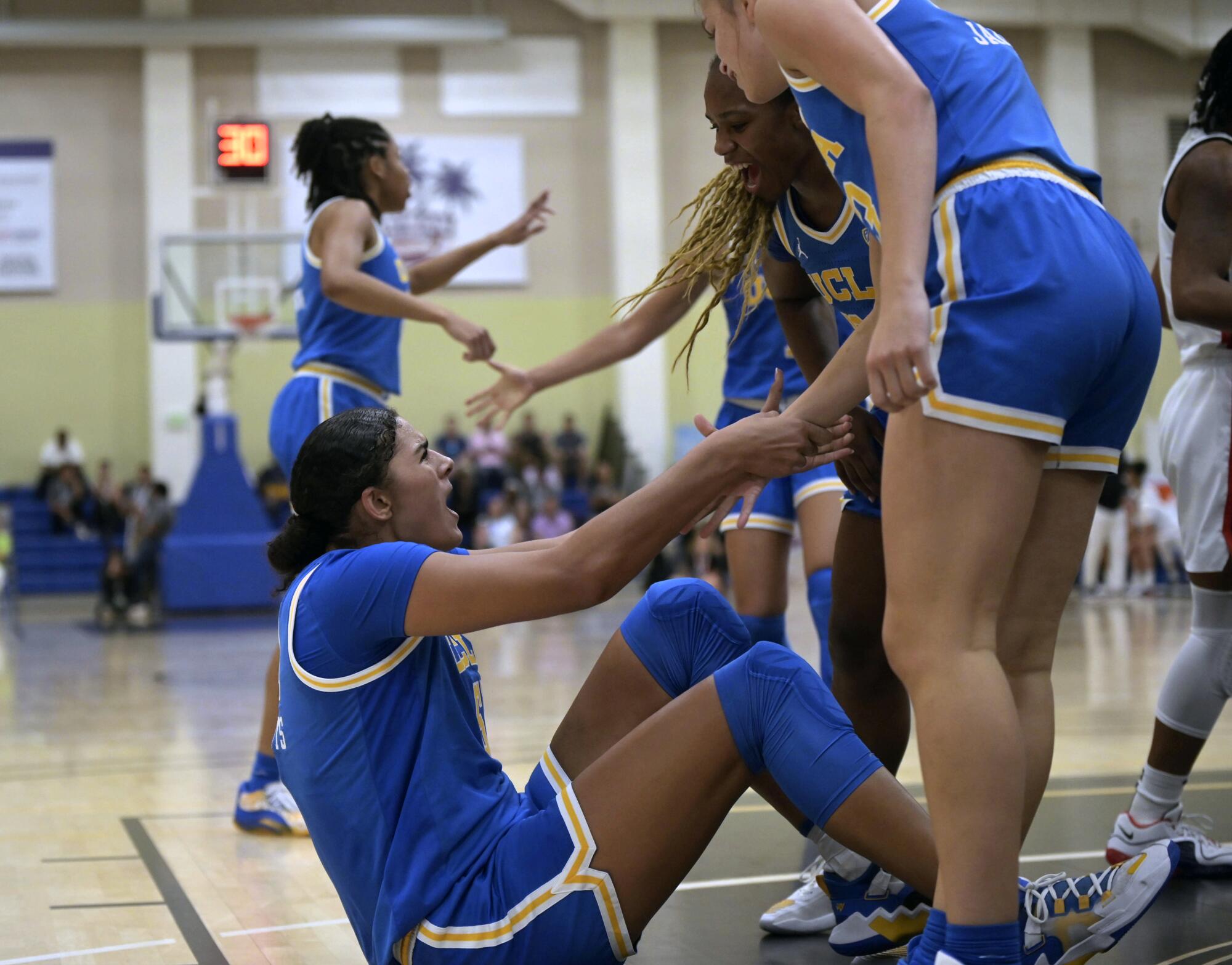 UCLA's Lauren Betts celebrates and gets help standing up from teammates after scoring against UConn 