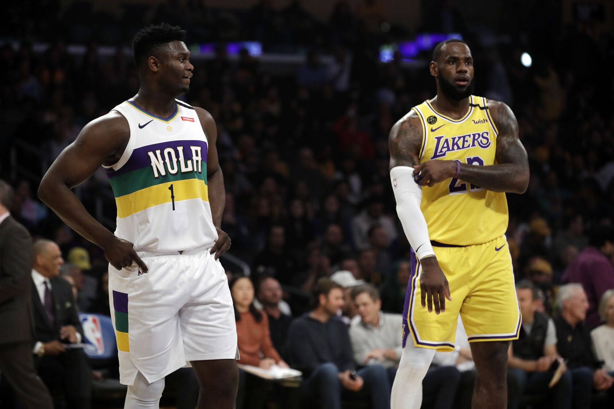 Pelicans forward Zion Williamson stands on the court next to Lakers forward LeBron James during a break in play.