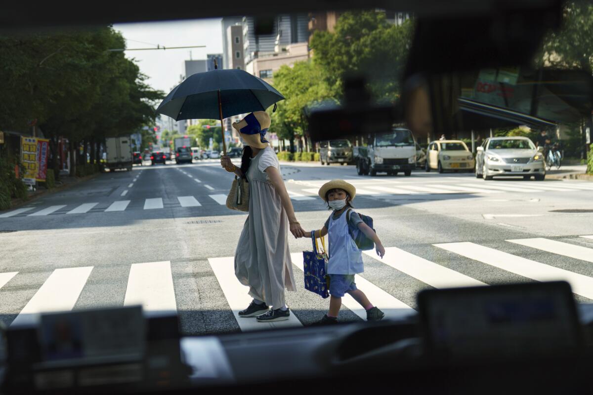 A pedestrian crossing a street with a child is seen through a taxi window in Tokyo.