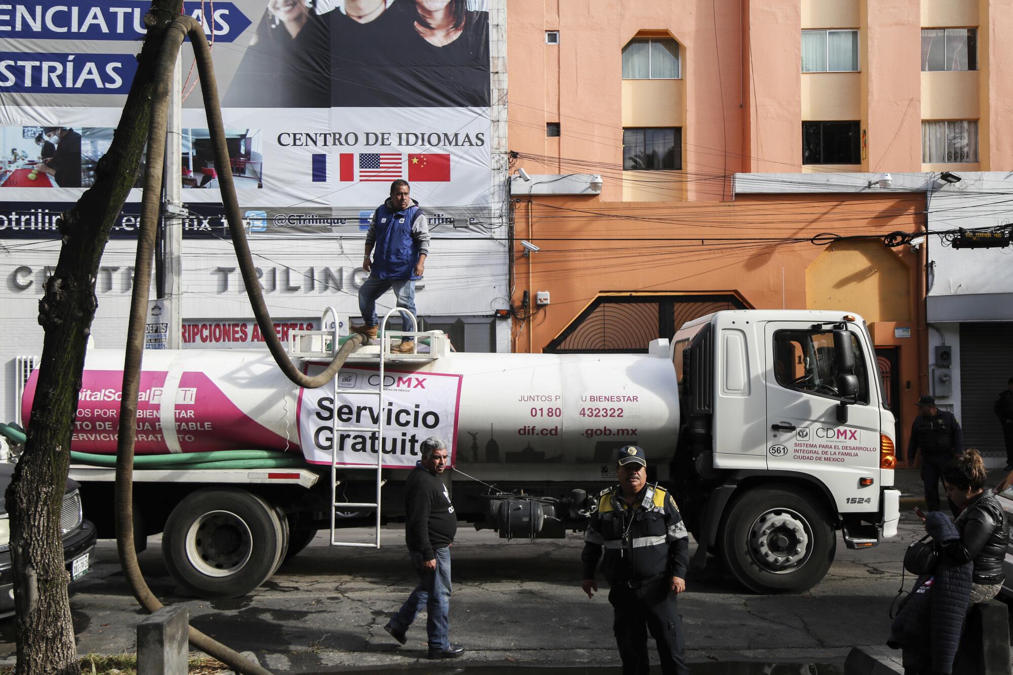 墨西哥城，一名男子站在一艘水罐车顶上。