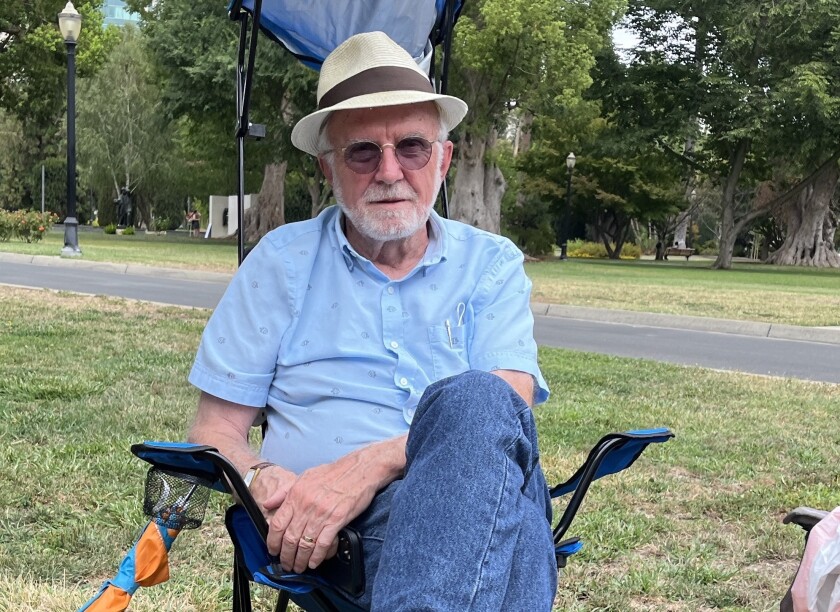 Bob Britton sits in a camp chair in front of the State Capitol in Sacramento.
