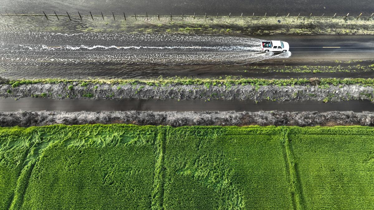 A vehicle travels along the flooded Garces Highway.