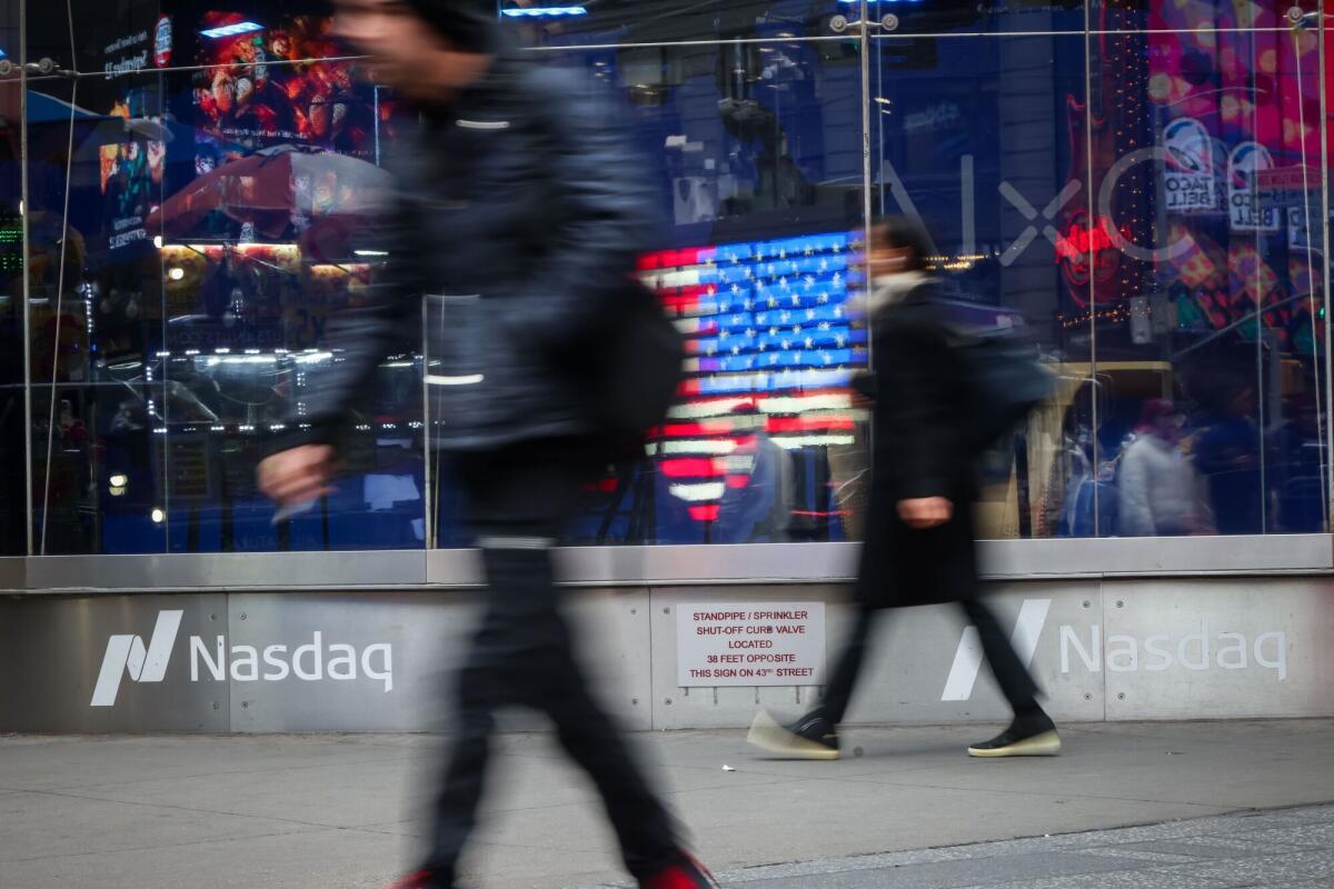 Pedestrians walk past the Nasdaq MarketSite in New York. 