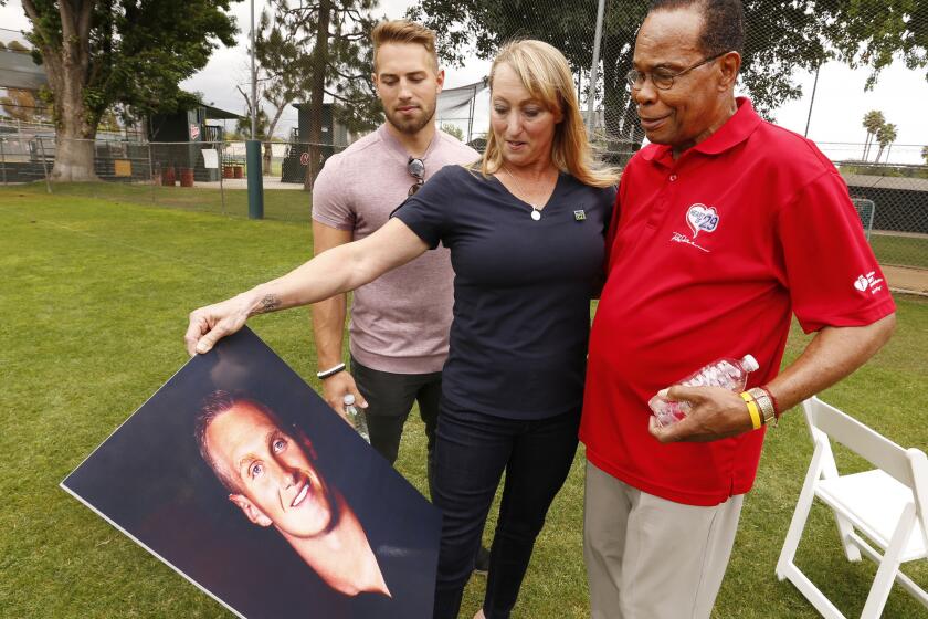 Brother Austin Reuland, left, mother Mary Reuland and Rod Carew look at a picture of Konrad Reuland, whose heart and kidney were transplanted into Carew in December. Konrad, a former NFL player, died at age 29 of a brain aneurysm.