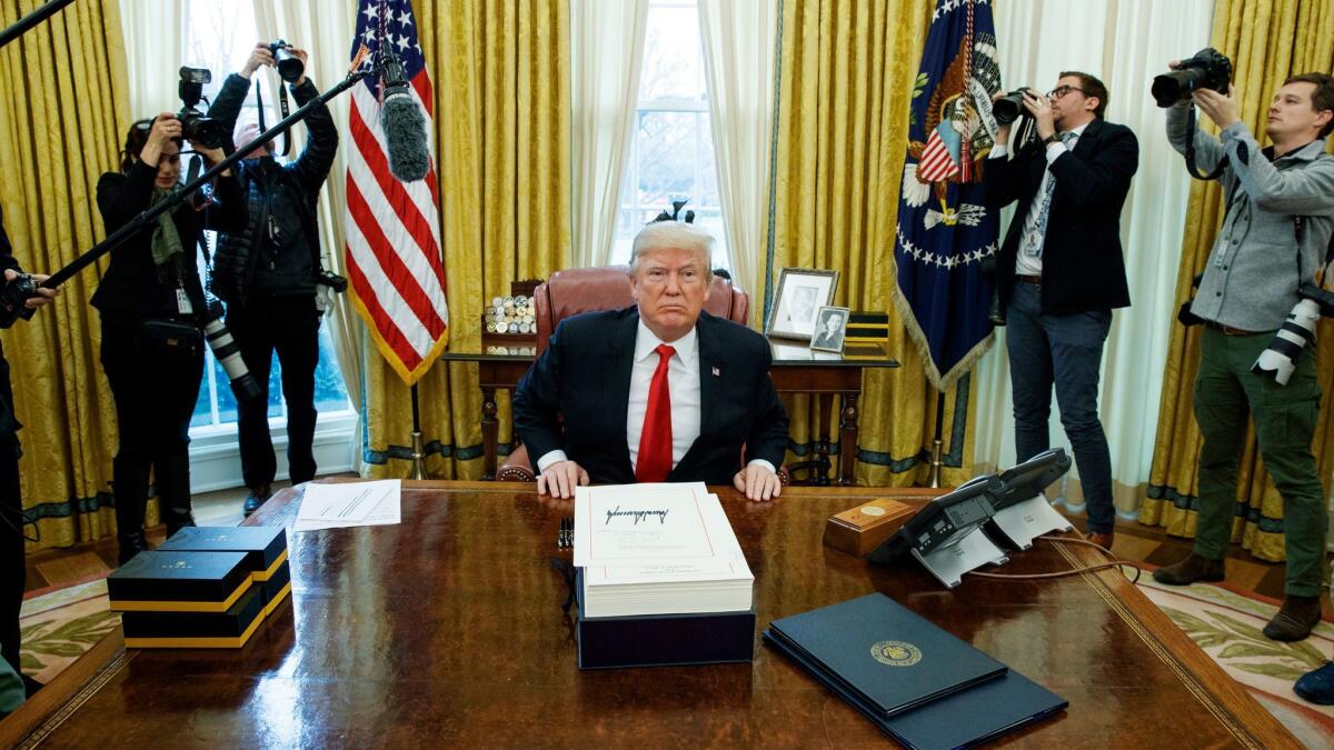 President Donald Trump offers pens to reporters after signing the tax bill and continuing resolution to fund the government, in the Oval Office in Washington on Dec. 22.