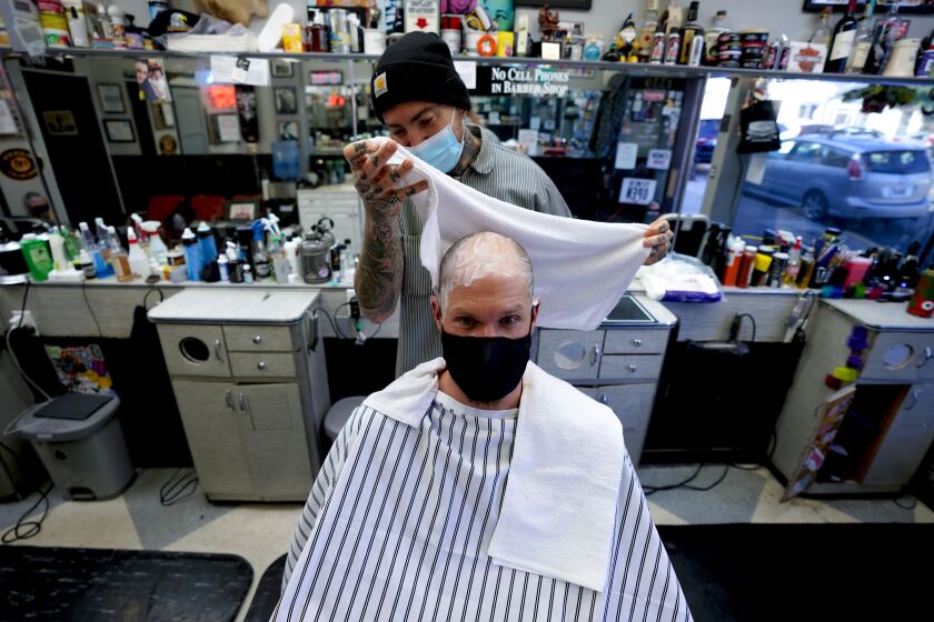 SAN DIEGO, CA - NOVEMBER 12: In Pacific Beach on Thursday, Nov. 12, 2020 in San Diego, CA., Rob Hammer from Encinitas gets a head shave from Mikal Zack at LeftyOs Barber Shop. Encinitas photographer Rob Hammer has spent the past eight years traveling the U.S. to capture images of old-school barbershops before they disappear. He's published the images, which include several from SD County, in coffee-table books. (Nelvin C. Cepeda / The San Diego Union-Tribune)