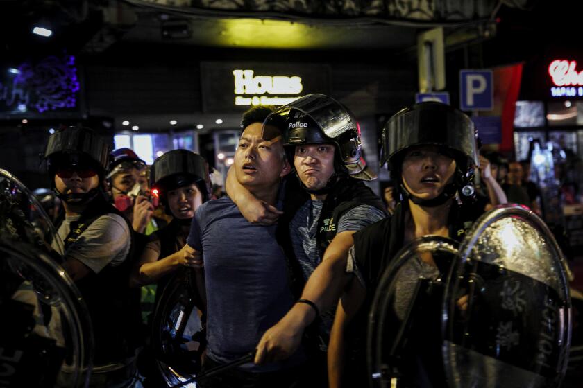 Marcus Yam  Los Angeles Times AN OFFICER warns people to step back as police arrest a man near Mong Kok station in Hong Kong, where a citywide strike followed a violent weekend.