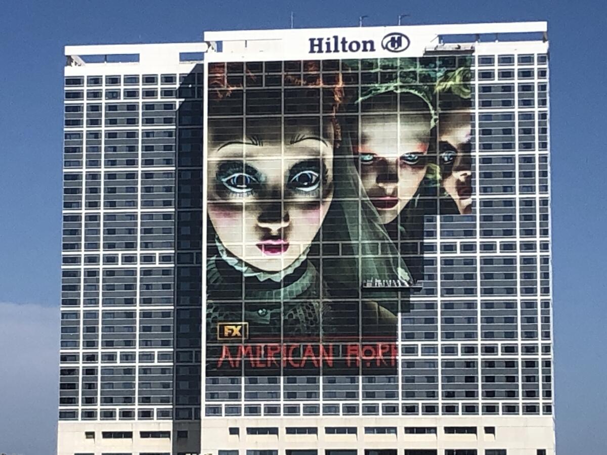 The Hilton San Diego Bayfront is wrapped with an advertisement for  "American Horror Story." 