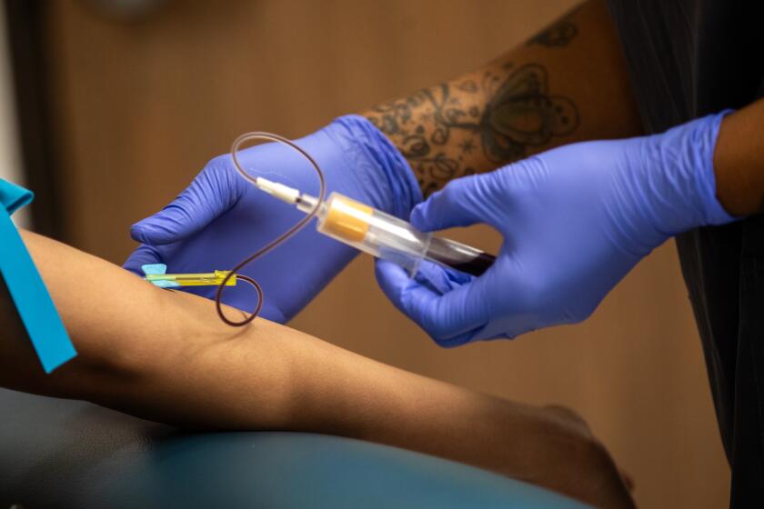 Los Angeles, CA - September 05: Phlebotomist Latrell Anderson, right, draws blood at the Aids Healthcare Foundation Wellness Center - Western on Tuesday, Sept. 5, 2023, in Los Angeles, CA. Los Angeles County's policy related to STD testing is about to change. (Francine Orr / Los Angeles Times)