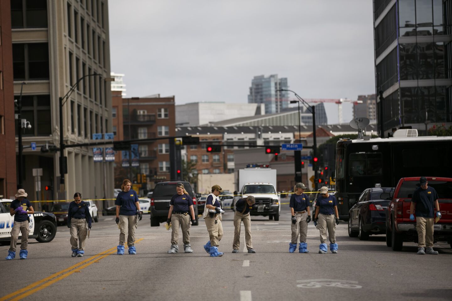 Investigators walk in a formation on Lamar Street to comb through the crime scene outside El Centro College in Dallas where a gunman killed five police officers and wounded seven others.