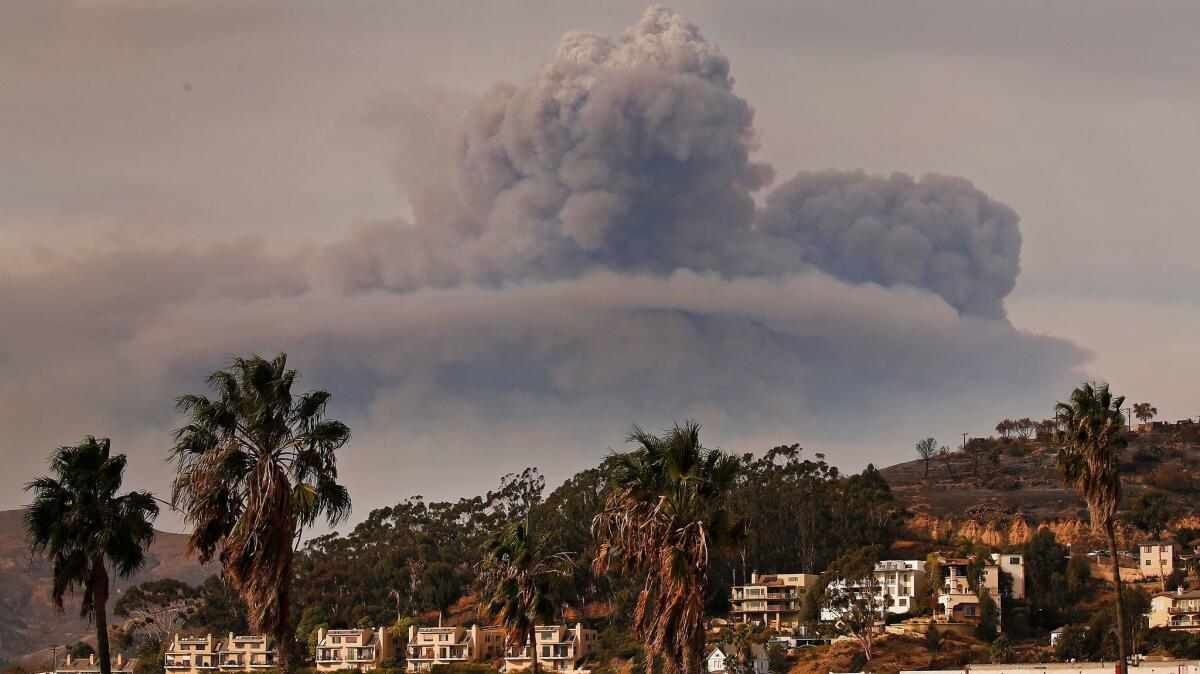 A cloud of smoke rises to the north of downtown Ventura, as seen Sunday afternoon from the Ventura Pier.