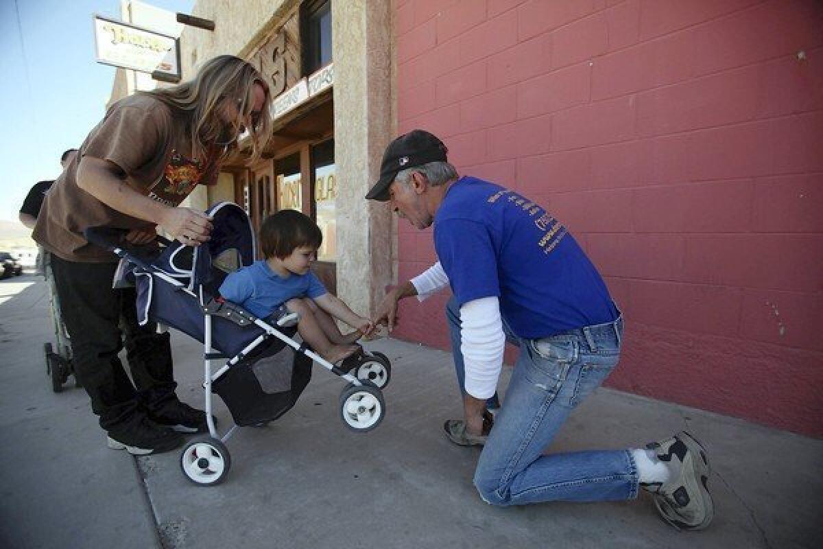 Travis Flagg, left, and his son Ambrose Corey greet their friend Rick Bogdanich outside the Desert Manna shelter in Barstow. Bogdanich, 58, is an unemployed construction worker living at the shelter. He is undecided about whom to vote for in the presidential race and thinks neither candidate will be of much help to him.