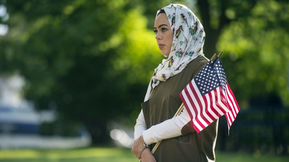 A Muslim woman holds American flags at an interfaith prayer service in Flint, Mich., on June 22.