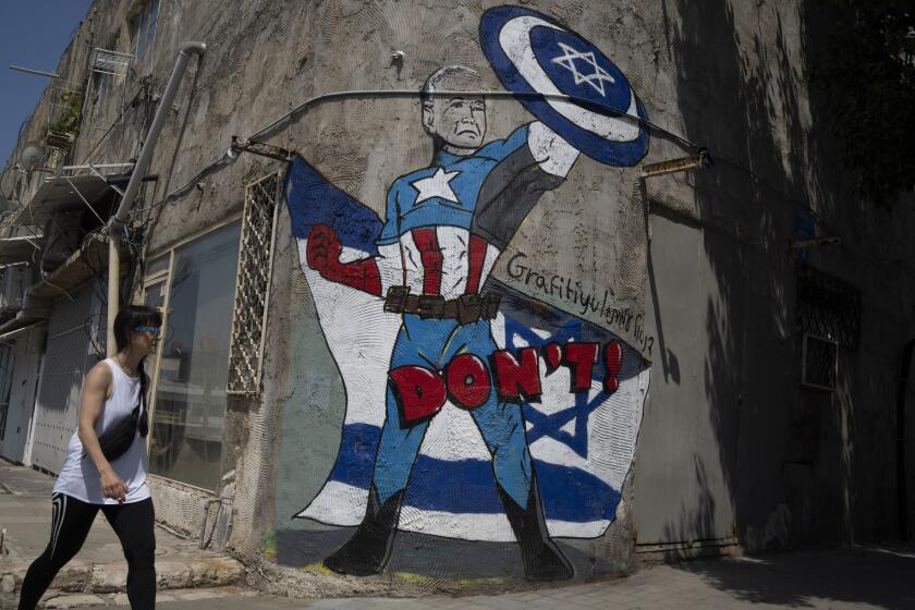 Una mujer pasa junto a un mural que representa al presidente estadounidense Joe Biden como un superhéroe que defiende a Israel en una calle de Tel Aviv, Israel, el domingo 14 de abril de 2024. (Foto AP/Leo Correa)