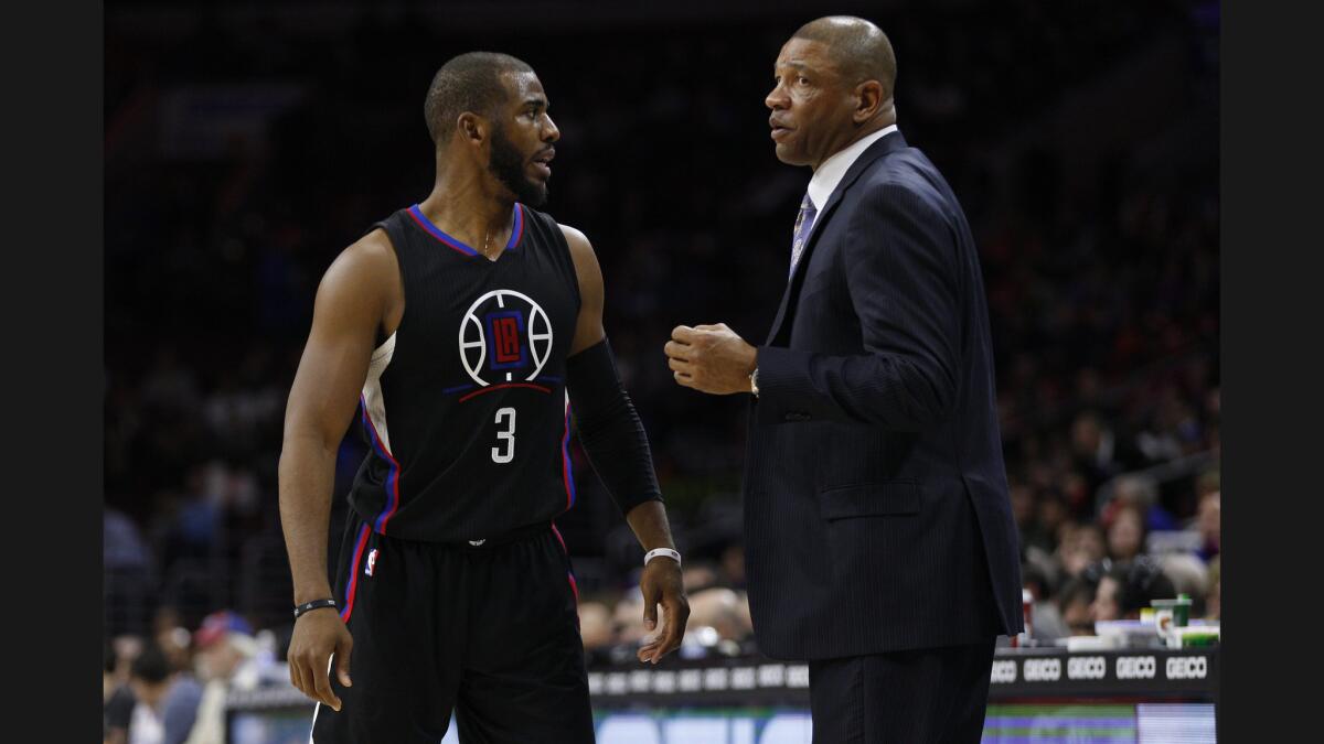 Clippers' head coach Doc Rivers talks thing over with Chris Paul in first half of game against 76ers.