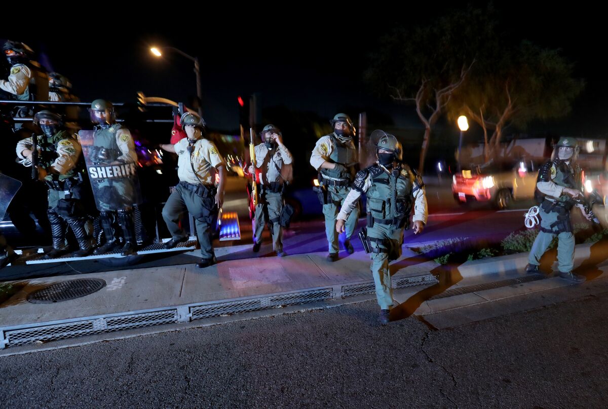Los Angeles County sheriff's deputies disperse protesters marching in West Hollywood on Friday night.