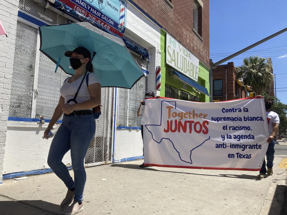 Daisy Arvizu, left, participates in a street march in support of immigrant rights on Aug. 26, 2021, in El Paso, Texas, amid lingering concerns about gun violence targeting immigrants. She was at work inside a Walmart in El Paso in August 2019 when a gunman opened fire in a shooting that killed 23 people, spurring her husband, Martin Portillo, to later to buy a handgun for their protection. A new "constitutional carry" law in Texas allows most gun owners age 21 and older to carry a holstered handgun — concealed or not — in public without getting a license and related training. (AP Photo/Morgan Lee)