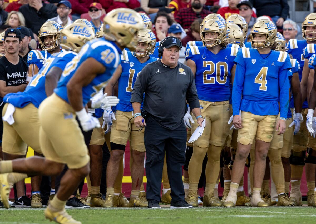 UCLA coach Chip Kelly reacts on the sidelines while standing alongside his players.