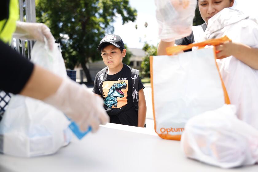 LOS ANGELES-CA-AUGUST 21, 2023: Renato Ramirez, 8, center, and his mom Daniela Fuentes, right, pick up meals at a Grab and Go food site at Fremont High School, set up by LAUSD on August 21, 2023. All LAUSD schools are closed today due to Hurricane Hilary. (Christina House / Los Angeles Times)