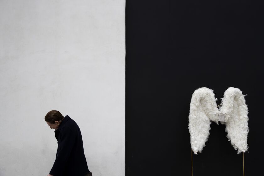 Un hombre camina junto a unas alas de ángel exhibidas en una tienda en Beverly Hills, California, el martes 7 de mayo de 2019. (AP Foto/Jae C. Hong, Archivo)