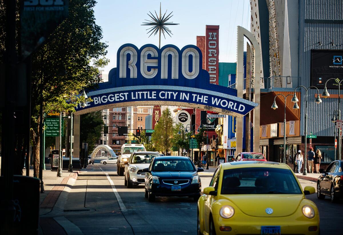 Cars and pedestrians pass by the Reno Arch, an iconic landmark that spans Virginia Street in downtown Reno.