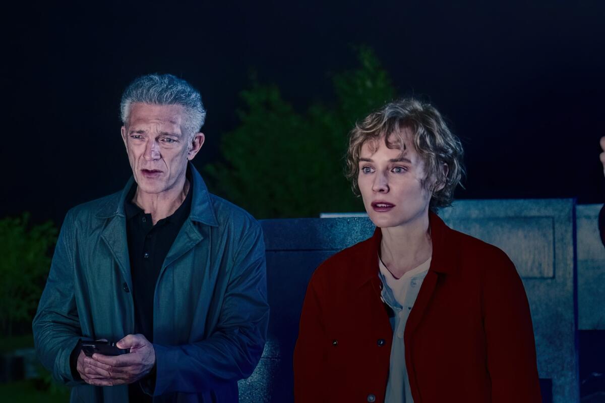 A man and a woman looking startled in a graveyard at night