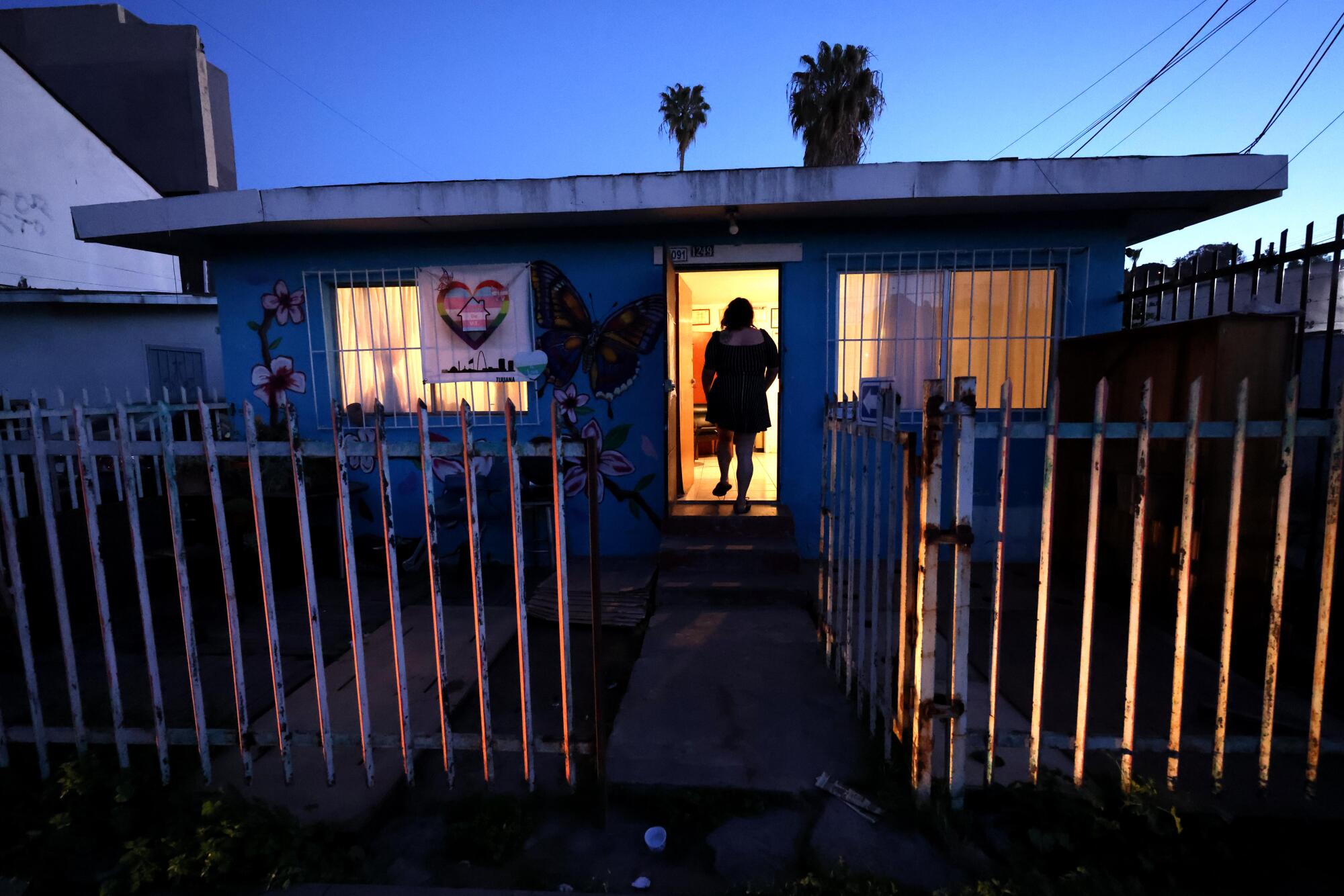 A woman seen in silhouette at the entrance of a building with a light inside