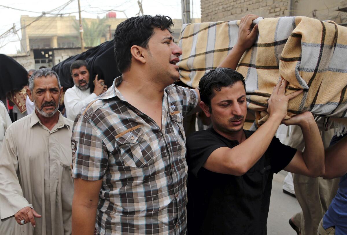 Friends and family of victims of a suicide bombing grieve as they carry coffins near the site of an attack in Baghdad on Oct. 12.