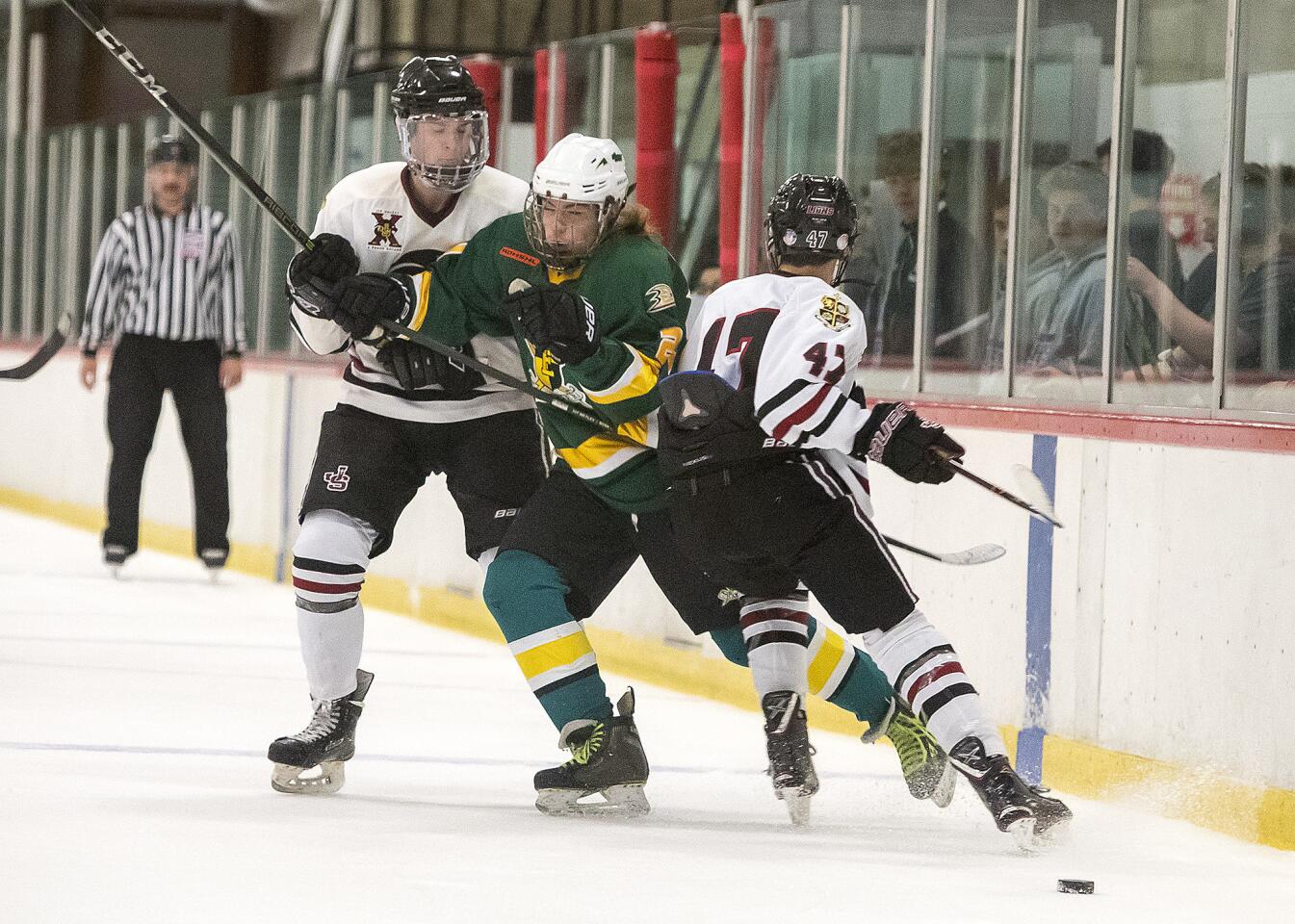 Edison's James McGuire gets hit by JSerra's John Dwyer, left, and Max Lynch during an Anaheim Ducks High School Hockey League Division 1 playoff game on Thursday, March 8.