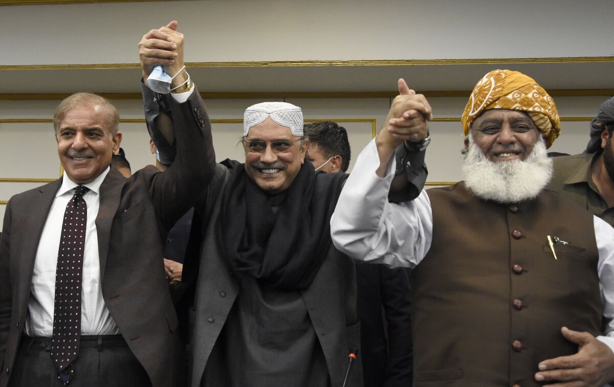 Pakistan's opposition party leaders from left to right, Shahbaz Sharif, Asif Ali Zardari and Fazalur Rehman raise their hands during a press conference, in Islamabad, Pakistan, Tuesday, March 8, 2022. In a joint move Pakistan's opposition parties submitted a much-awaited no-confidence motion against Prime Minister Imran Khan in the National Assembly secretariat, seeking his removal through a vote. (AP Photo)