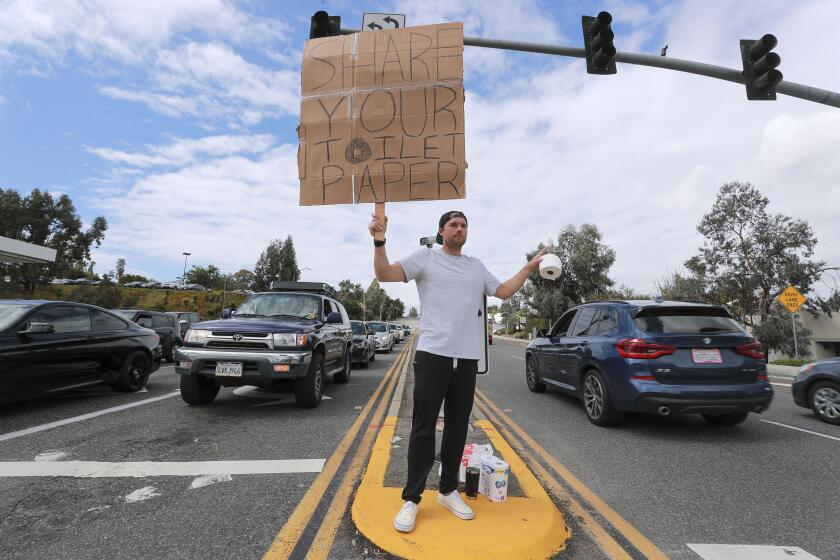 Encinitas resident Jonny Blue, 33, who is a physical therapist, makes a request for toilet paper so that he can in turn give it to drivers that need it while standing at the intersection of Encinitas Boulevard and El Camino Real on Saturday, March 14, 2020 in Encinitas, California. Blue said that after learning that friend of his, who has children, was unable to buy toilet paper due to people buying up large amounts of toilet paper because of the coronavirus, he decided to start a sort of free exchange of toilet paper in hopes that people of the community would share theirs with others who can't find any.