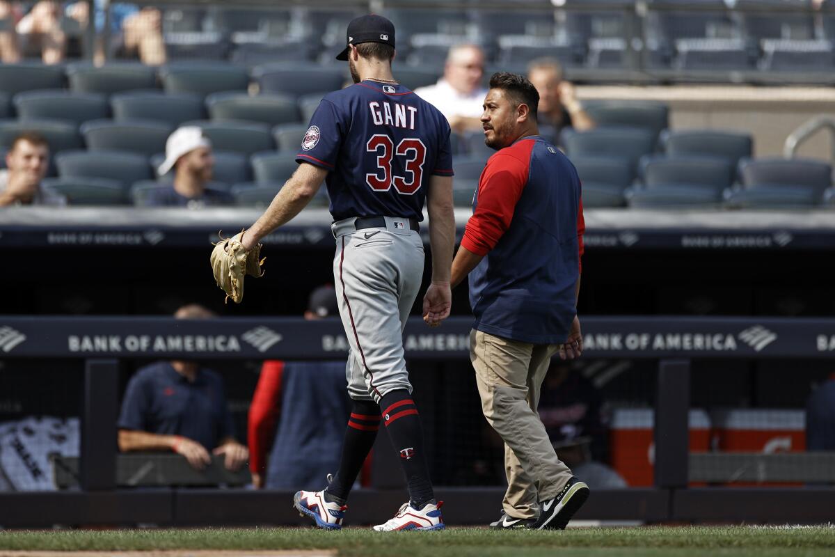 Minnesota Twins pitcher John Gant (33) walks off the field with a team trainer after being taken out of the game against the New York Yankees during the first inning of a baseball game on Monday, Sept. 13, 2021, in New York. (AP Photo/Adam Hunger)