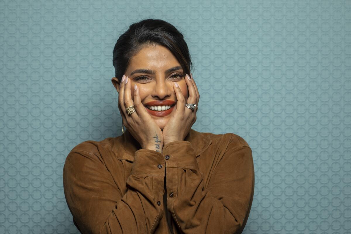 Priyanka Chopra Jonas smiles with her hands on her face