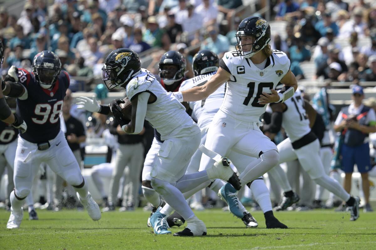 Jacksonville Jaguars quarterback Trevor Lawrence hands the ball off to running back Travis Etienne Jr.