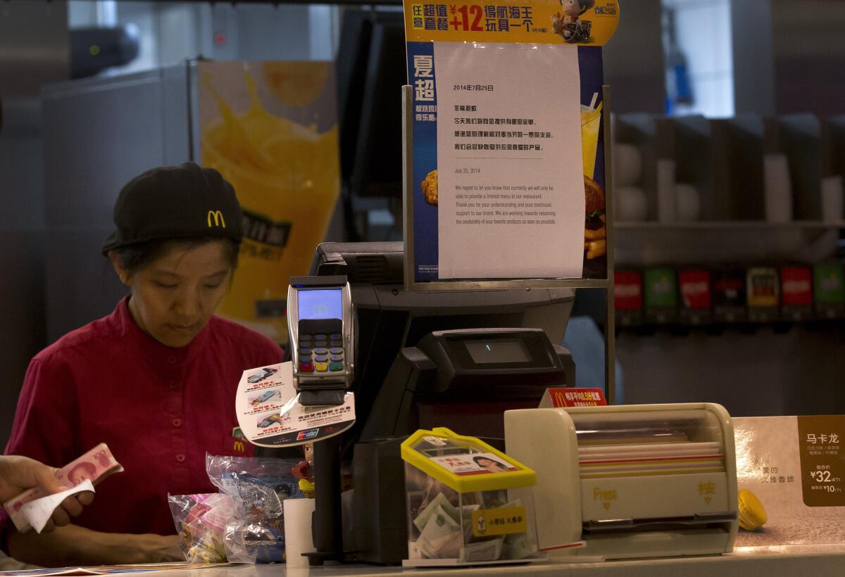 Workers count Chinese yuan banknotes at a McDonald's restaurant in Beijing. A notice at the counter announces a limited menu.