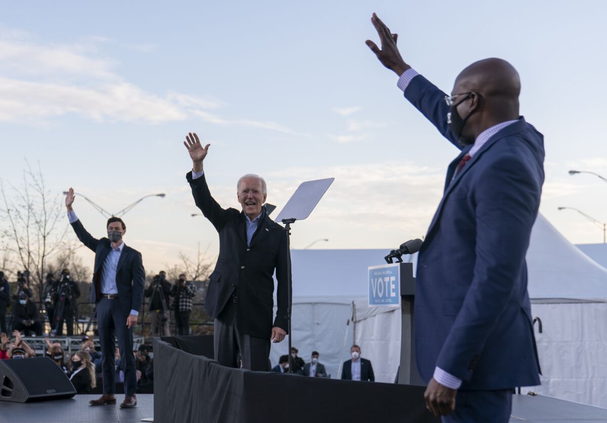 President-elect Joe Biden stands on stage with the Rev. Raphael Warnock and Jon Ossoff in Atlanta.