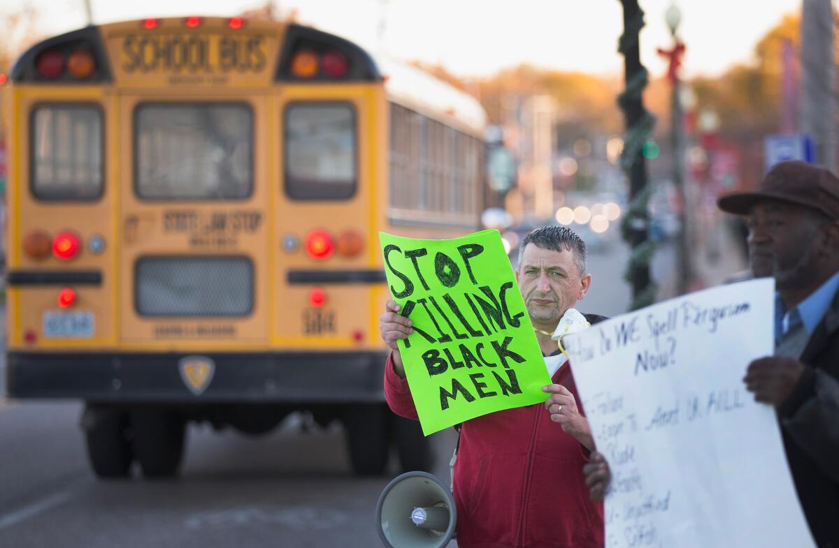 A school bus passes demonstrators protesting outside the police station in Ferguson, Mo., on Nov. 10.