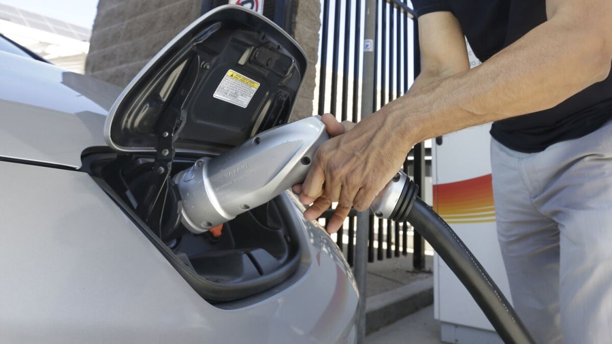 A man plugs a charger into his electric vehicle.