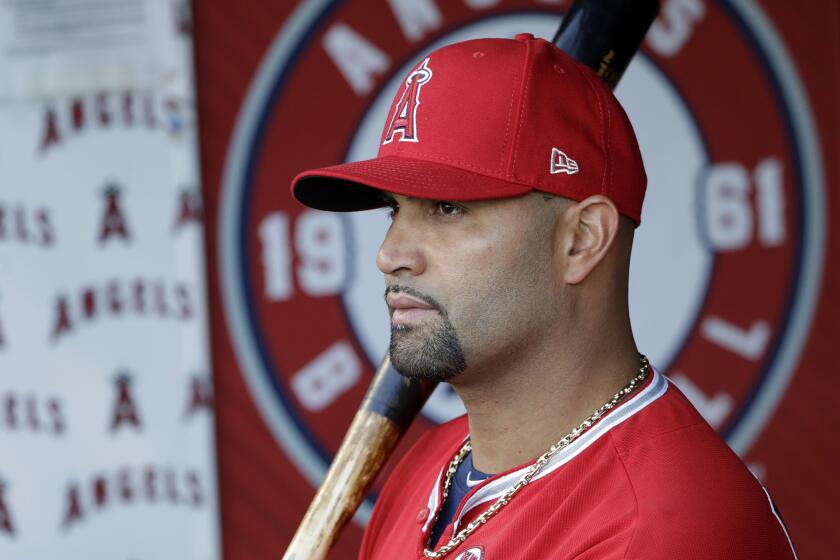 Los Angeles Angels' Albert Pujols holds a bat in the dugout before the start of a baseball game.