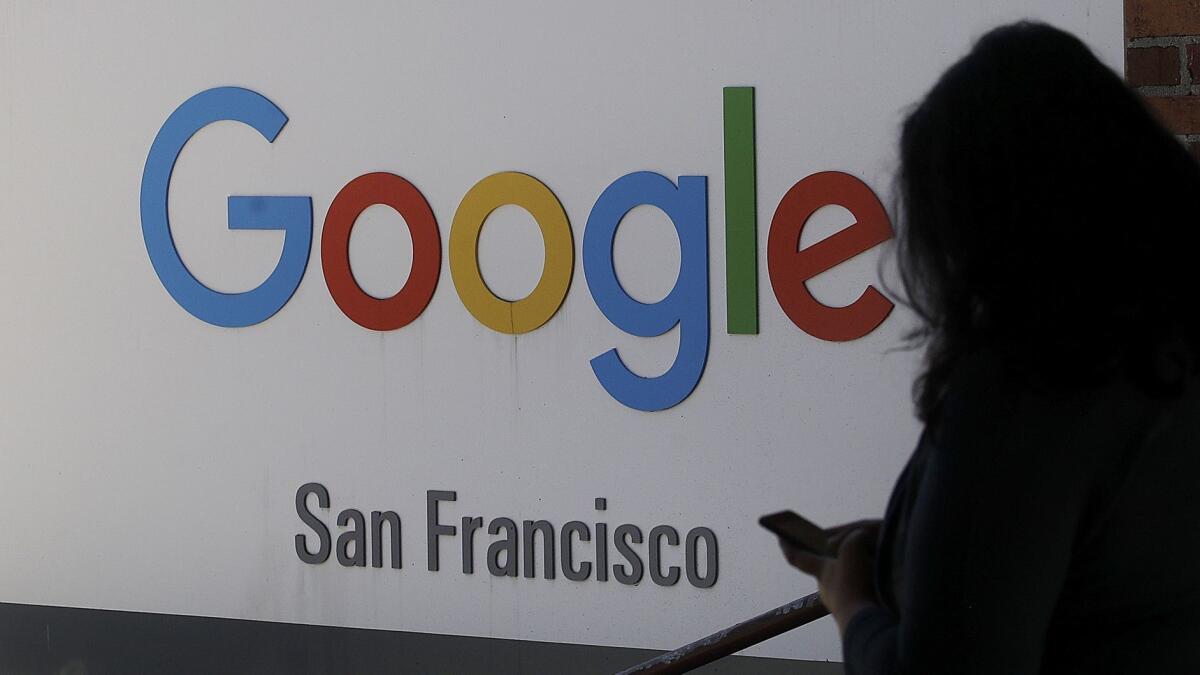 A woman walks past a Google sign in San Francisco.