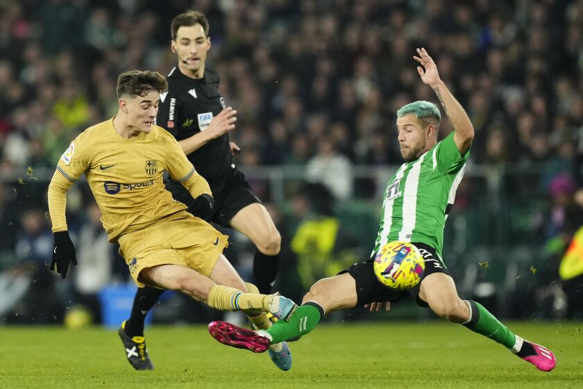 Barcelona's Gavi, left, fights for the ball with Betis' Aitor Ruibal during a Spanish La Liga soccer match between Real Betis and Barcelona at the Benito Villamarin stadium in Seville, Spain, Wednesday, Feb. 1, 2023. (AP Photo/Jose Breton)