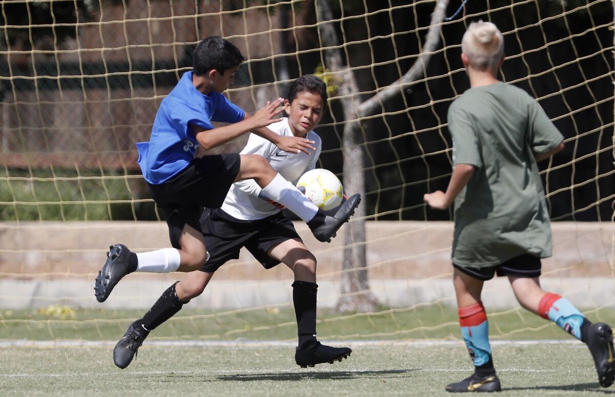 Killybrooke Elementary goalkeeper Danny Rivas, center, makes a save against Lincoln's Gavin Karam, left, during a boys' fifth- and sixth-grade Gold Division pool-play match at the Daily Pilot Cup on Wednesday at Jack R. Hammett Sports Complex.
