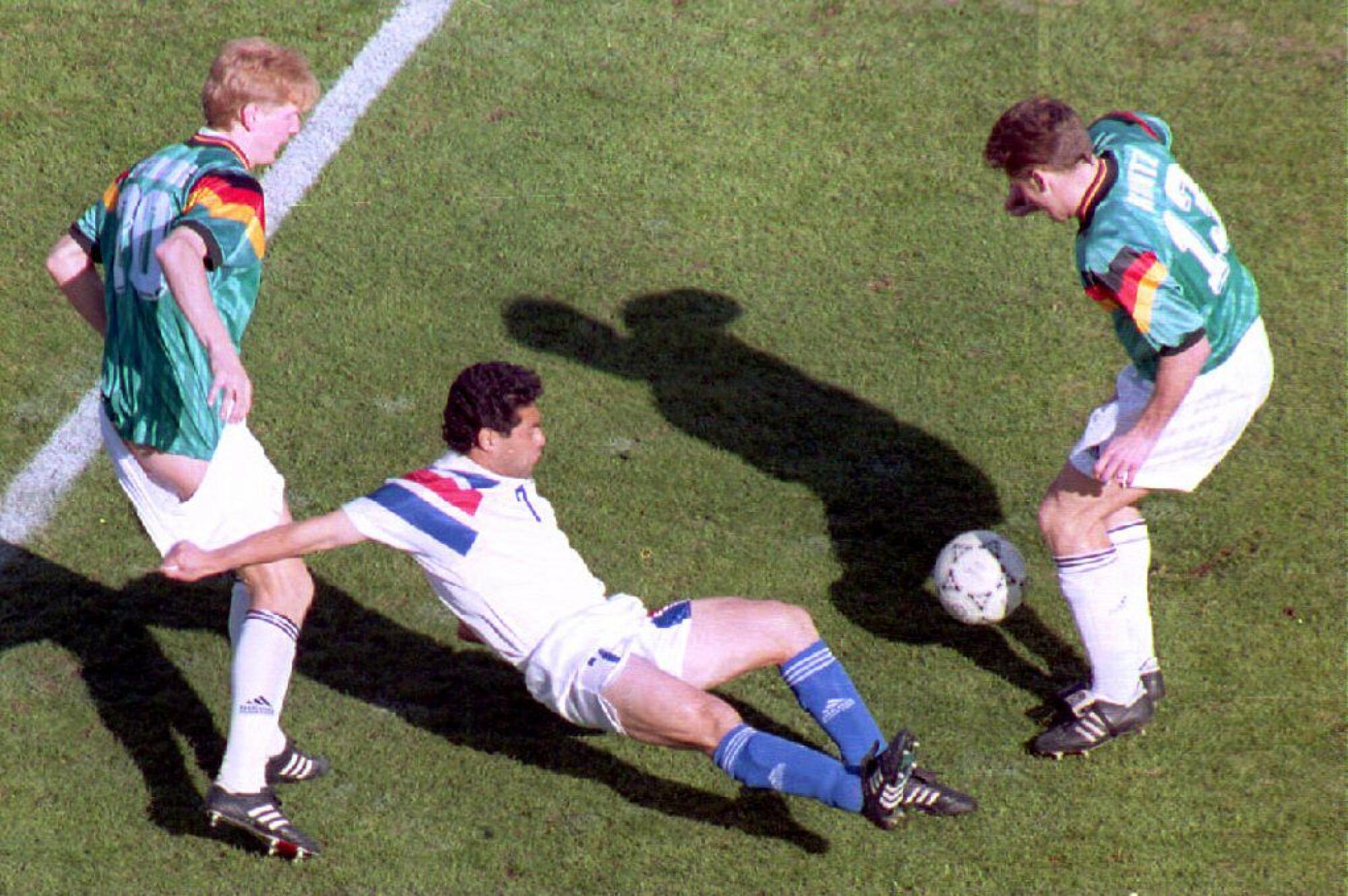 Germany team player Stefan Effenberg's shorts are tugged U.S. player Hugo Perez as German Stefan Kuntz goes for the ball