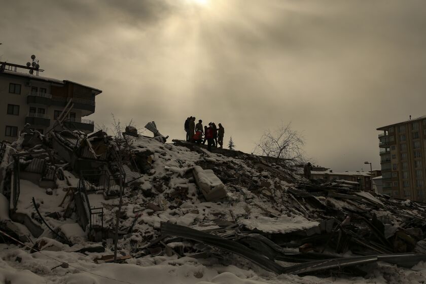 People try to reach people trapped under the debris of a collapsed building in Malatya, Turkey, Tuesday, Feb. 7, 2023. Search teams and aid are pouring into Turkey and Syria as rescuers working in freezing temperatures dig through the remains of buildings flattened by a magnitude 7.8 earthquake. (AP Photo/Emrah Gurel)