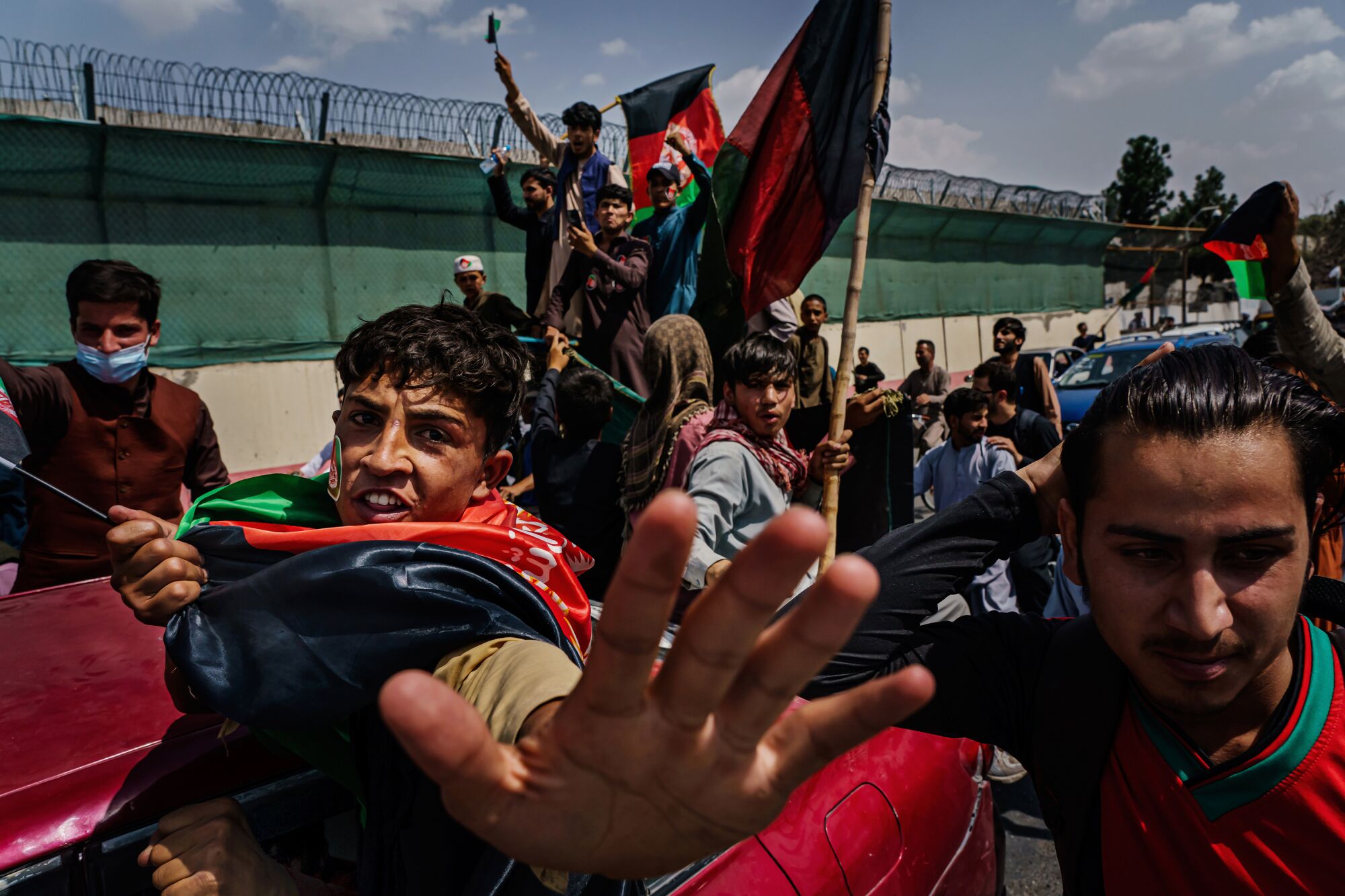 Anti-Taliban protesters march, one tries to block the photographer's lens