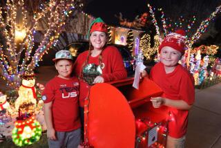Elizabeth Bruckner stands with her sons A.J., 7, at left, and Wolfie, 10, at their "Santa Mail" box in front of their Carlsbad home.