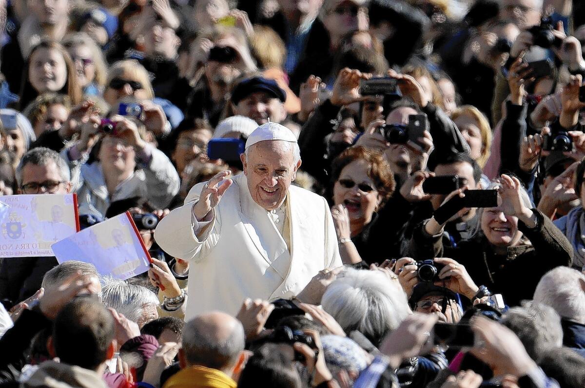 Pope Francis waves during his weekly audience at St. Peter's Square. Sixty percent of non-Catholics and 85% of Catholics surveyed recently said they viewed the pontiff favorably.